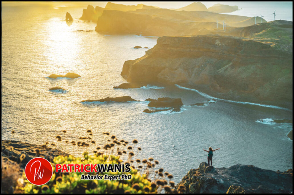 Person standing on a cliff overlooking the ocean at sunrise, symbolizing emotional freedom, hope, and the beginning of a new chapter after heartbreak.